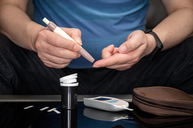 Man measures his blood sugar Glucometer blood sample test diabetes concept