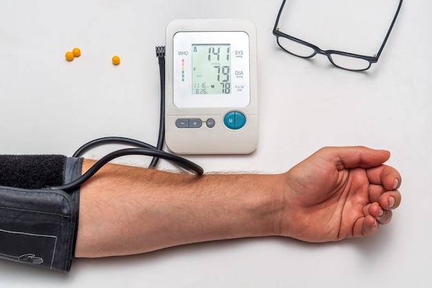 Un uomo misura la propria pressione sanguigna su un tavolo medico. prendersi cura della propria salute.