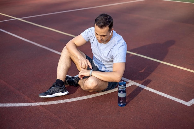 A man measures his pulse on a fitness bracelet while resting after a workout