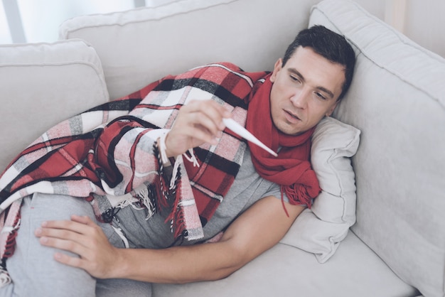 A man measures his temperature with electronic thermometer.