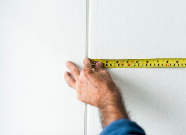 Man measuring the wall with a measuring tape