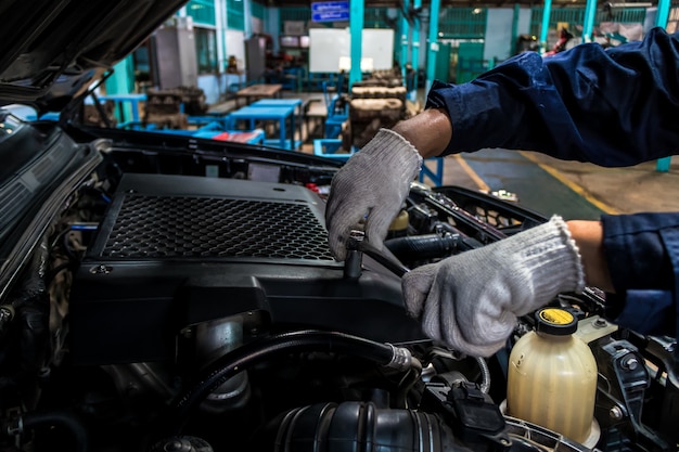 A man mechanic are repair a car Use a wrench and a screwdriver to work