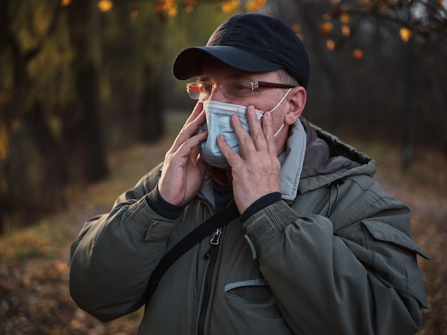 Man in medical mask in autumn park