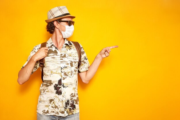 man in medical mask folded his hands in shape of heart as sign of love on yellow background