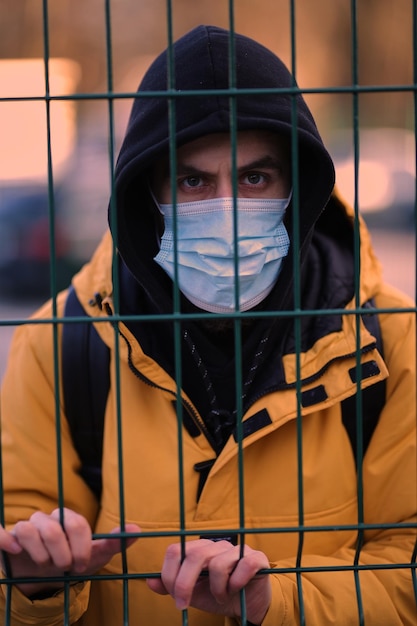 Мужчина в медицинской маске на улице Парень в медицинской маске во дворе