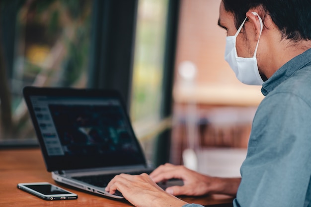 Man in medical mask using a laptop