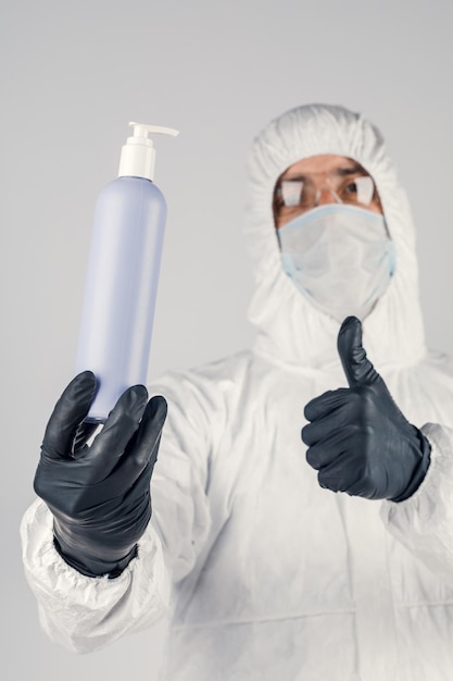 A man in a medical protective mask holding a hand sanitizer