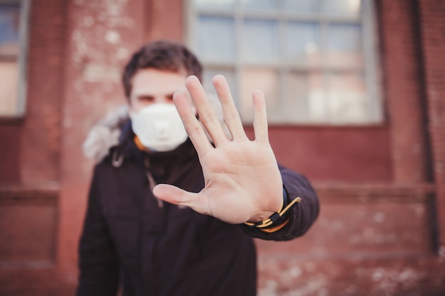 Человек в медицинской защитной маске, показывая жест остановки