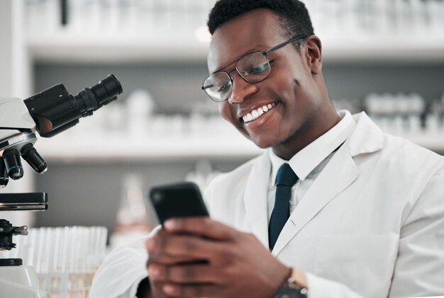 Man medical science and a phone in a laboratory for online communication email or website Happy African scientist person with smartphone typing medicine research social media or network database