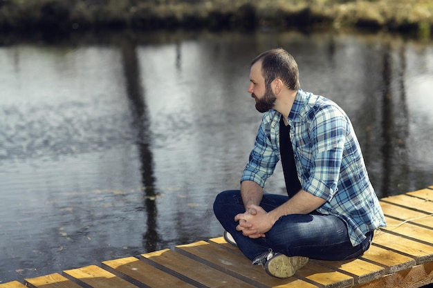 man meditating on the bank of a pond