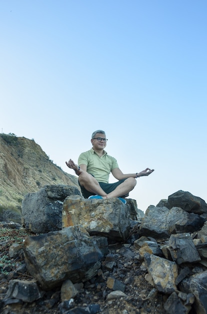 Uomo che medita sulle rocce in riva al mare