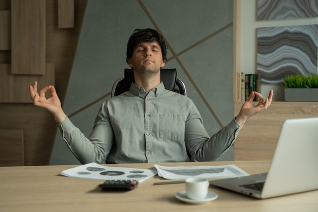 Man mediteert op kantoor om te gaan met stress zakenman die yoga doet aan een bureau in een modern kantoor