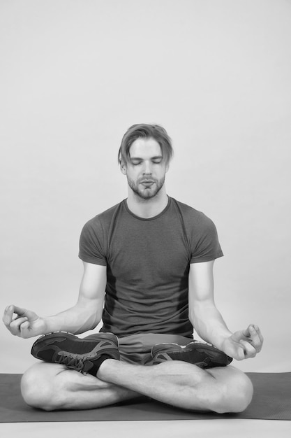 Foto man mediteert op yogamat sportman ontspan in lotushouding mode-atleet oefent yoga in de sportschool meditatie voor de gezondheid van lichaam en geest meditatie of zen- en vredesconcept