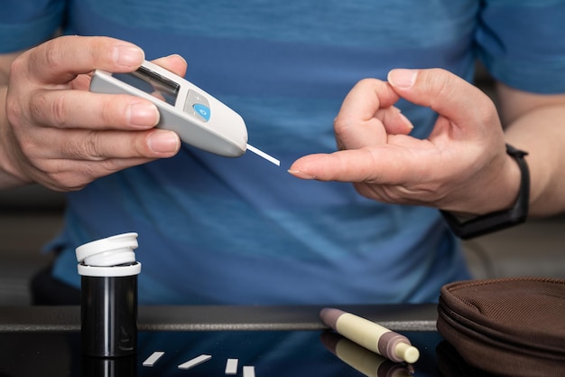 Man meet zijn bloedsuiker Glucometer bloedmonster test diabetes concept