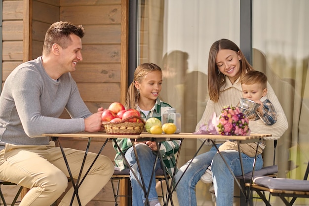 Man, meisje en vrouw kijken naar kind zittend aan tafel