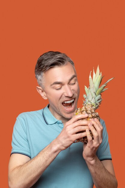 Man met ananas in de buurt van open mond