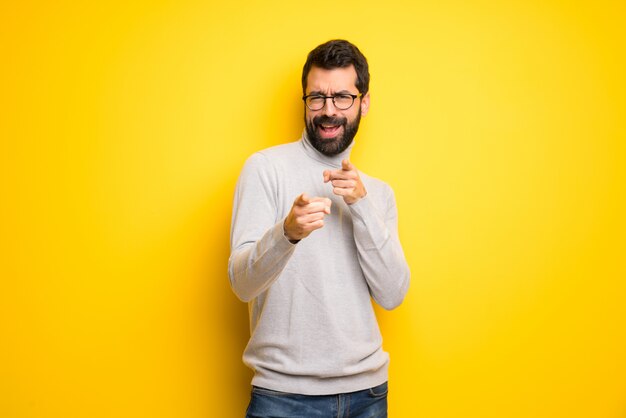 Man met baard en coltrui naar voren wijzen en glimlachen