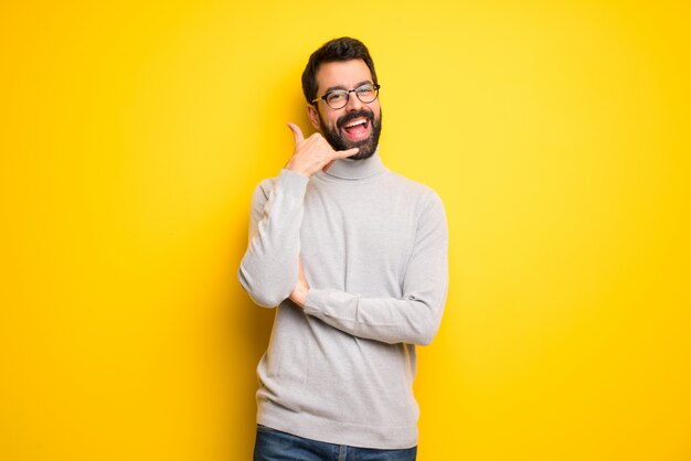 Man met baard en coltrui telefoon gebaar maken. bel me terug teken