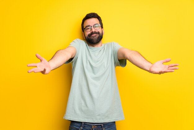 Man met baard en groen shirt presenteren en uitnodigen om te komen met de hand