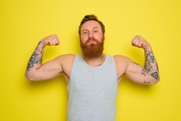 Foto man met baard en tatoeages laat met trots zijn spierballen zien