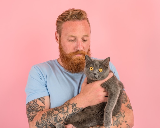 Man met baard en tatoeages streelt een grijze kat