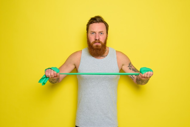 Foto man met baard en tatoeages traint met een elastiekje