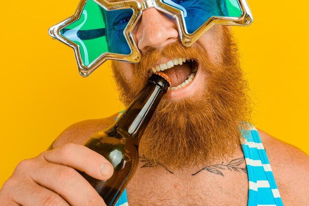 Man met baard en zonnebril drinkt bier