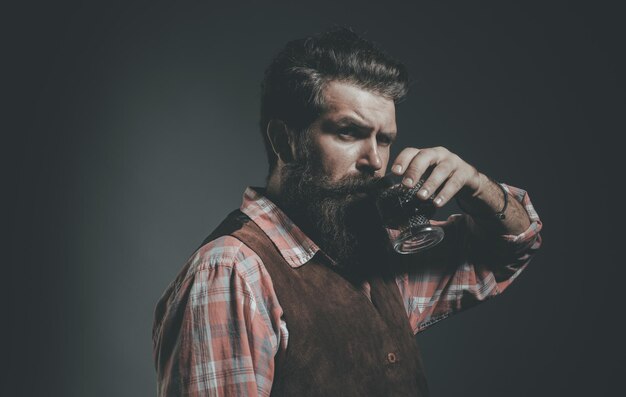 Man met baard houdt glas cognac vast Man of zakenman drinkt whisky op zwarte achtergrond