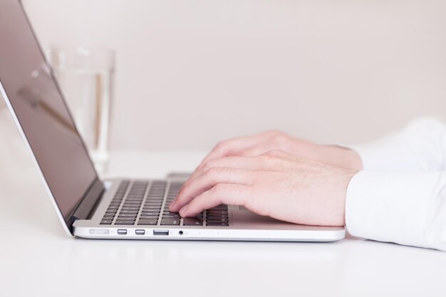 man met behulp van een moderne draagbare computer op een witte tafel