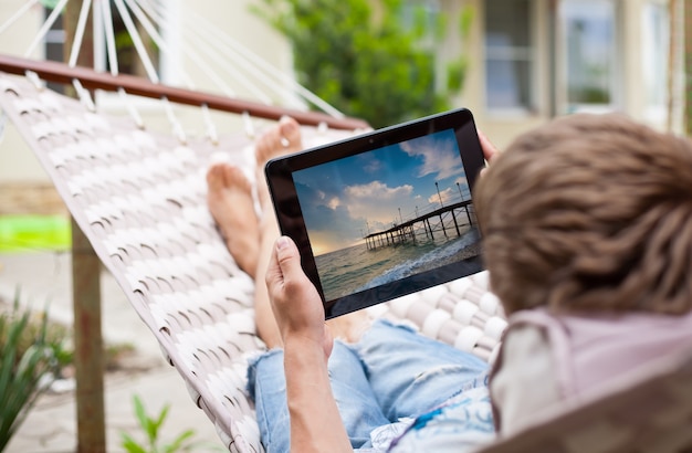 Man met behulp van een tablet-computer terwijl u ontspant in een hangmat