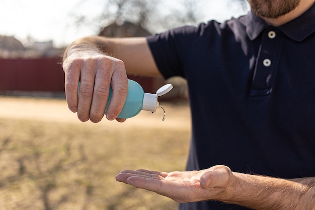 Man met behulp van kleine draagbare fles antibacteriële ontsmettingsmiddel