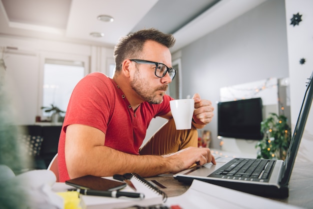 Man met behulp van laptop en koffie drinken