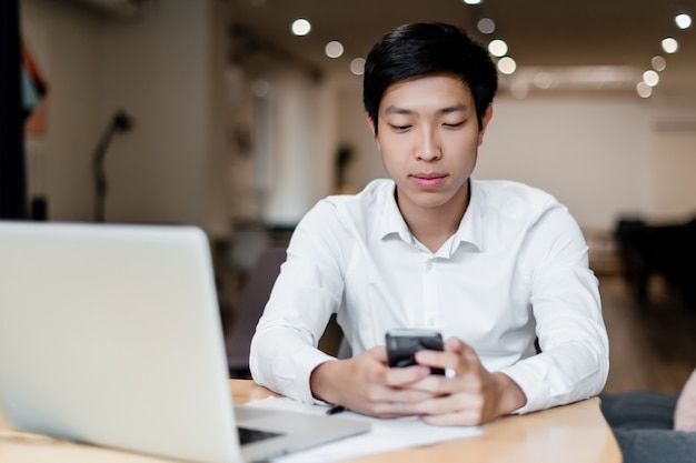 Man met behulp van mobiele telefoon en laptop