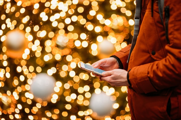 Man met behulp van slimme telefoon tegen verlichte kerstboom