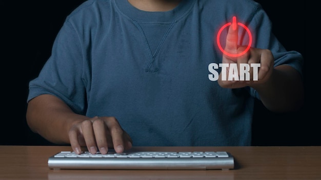 Man met blauwe t-shirt druk op de startknop om de computer te openen Concept van systeem begint te werken