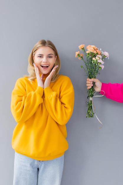 man met bloemen voor een vrouw in gele kleren op een grijze achtergrond Happy day