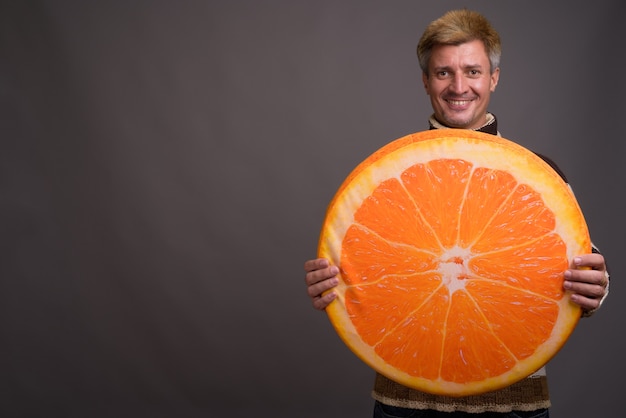 Man met blond haar met coltrui geïsoleerd tegen grijze muur