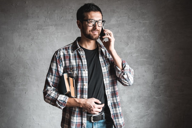 Man met boeken en kijken naar het scherm van een smartphone.