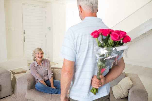 Man met boeket achter rug met vrouw zittend op de Bank