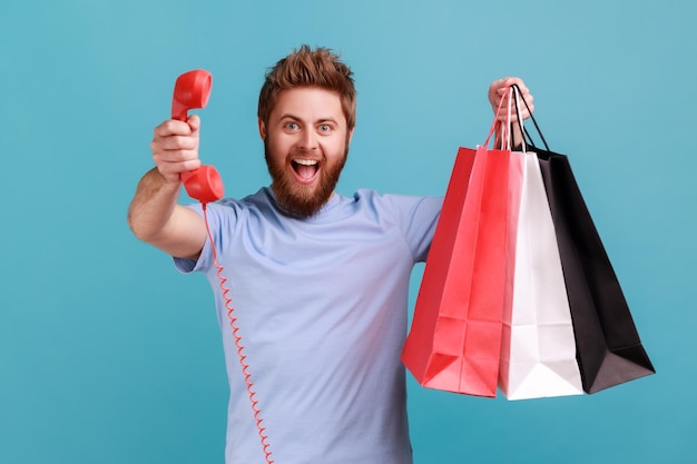 Man met boodschappentas en rood retro-telefoontje belt me opgewonden naar de camera te kijken