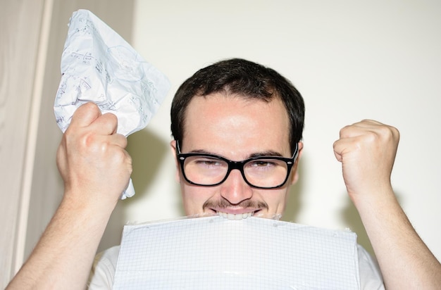 Man met bril die zijn handen opsteekt en papieren bijt die boos zijn op werkstress