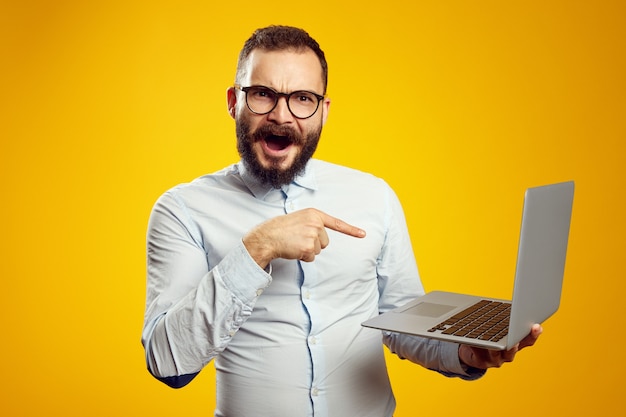 Man met bril schreeuwt van opwinding en wijst naar nieuwe laptop