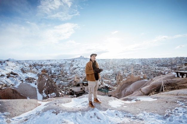Man met camera die bovenop de heuvel staat terwijl hij geniet van het uitzicht op cappadocië