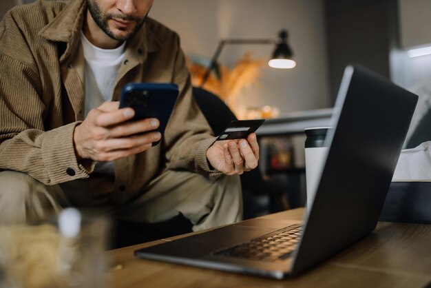 Foto man met creditcard en smartphone thuis gebruiken, online winkelen, internetbankieren, geld uitgeven