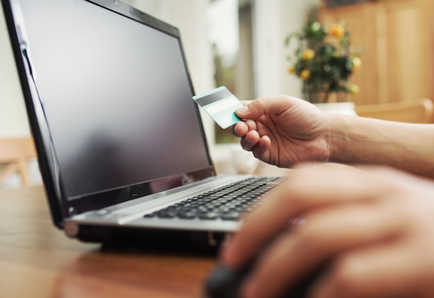 Man met creditcard in de hand en beveiligingscode invoeren met laptop toetsenbord