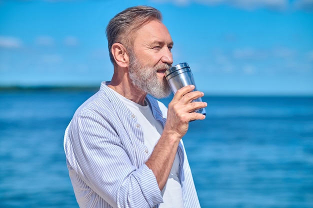 Man met drankje op de achtergrond van de zee