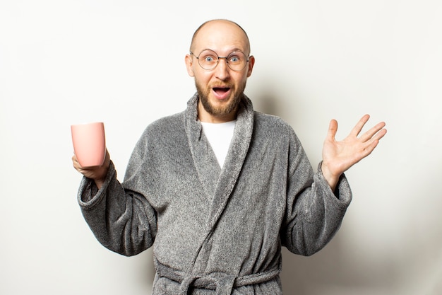 Man met een baard in een kamerjas en een bril met een kopje