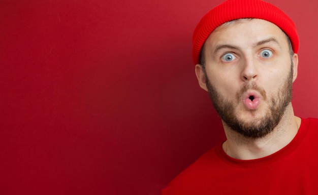 Man met een baard in een rode hoed opende verrast zijn mond. product reclame. banier