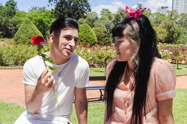 man met een bloem in zijn hand praat met zijn vriendin op een geliefde date in het park