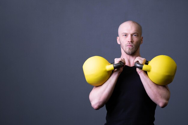 Man met een gele kettlebell sportschool anonieme jonge man voor fit tiener voor het plukken voor rubber